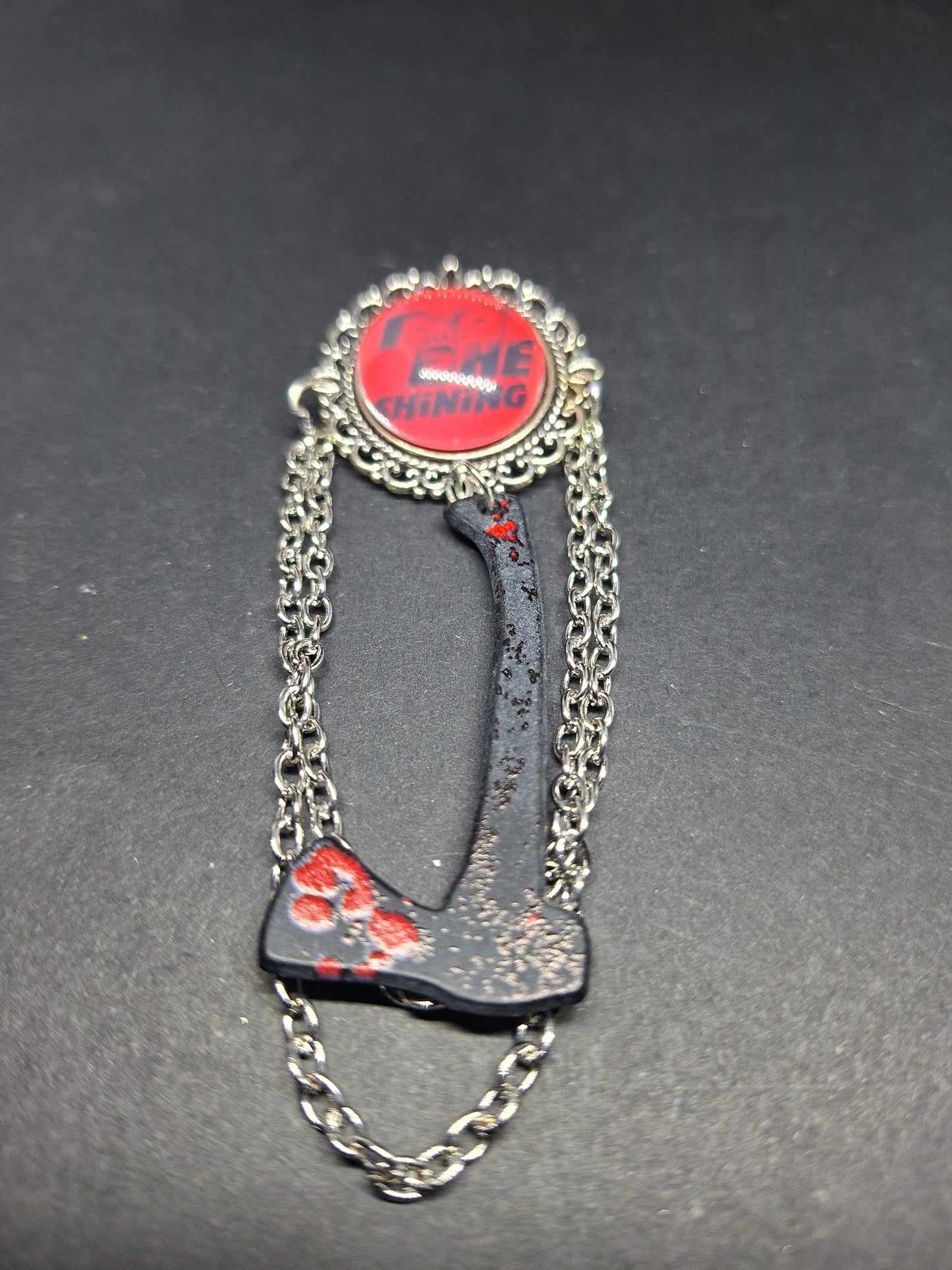 Ornate brooch with chains and blooded axe ,The shining inspired